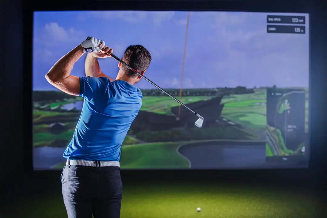 Player swinging a golf club at a simulator